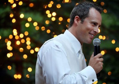 Man smiling holding a microphone with lights in the background